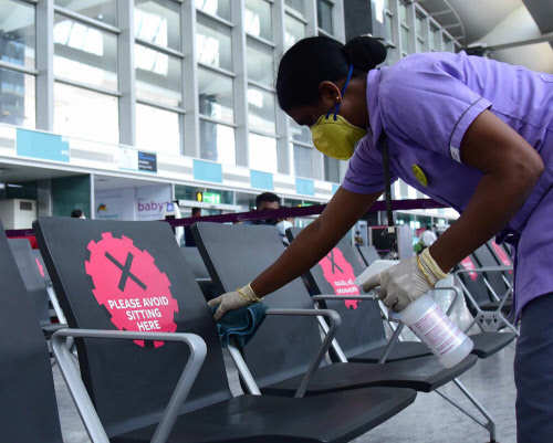 An airport official sanitizing the chairs