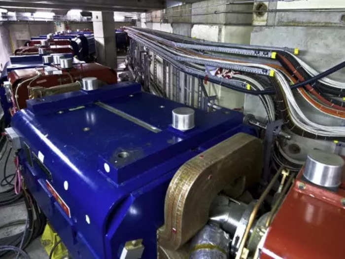 The energetic, chaotic-moving antiprotons are then fed into the Antiproton Decelerator, which uses powerful magnets, shown here in blue, to slow the antiprotons down and direct them around the ring of the Antiproton Decelerator.