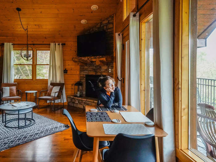 To the right of the living area, a dining table was placed next to floor-to-ceiling windows and a door that led to a covered balcony.