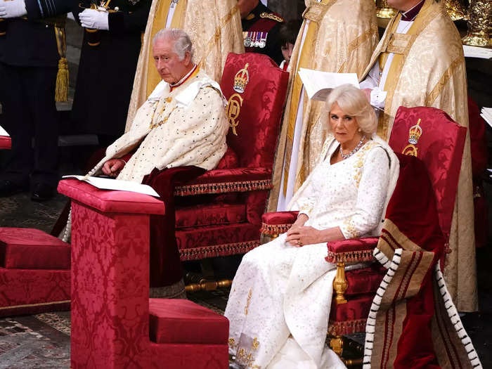 Both King Charles and Queen Camilla bore somber expressions as they sat on their thrones.