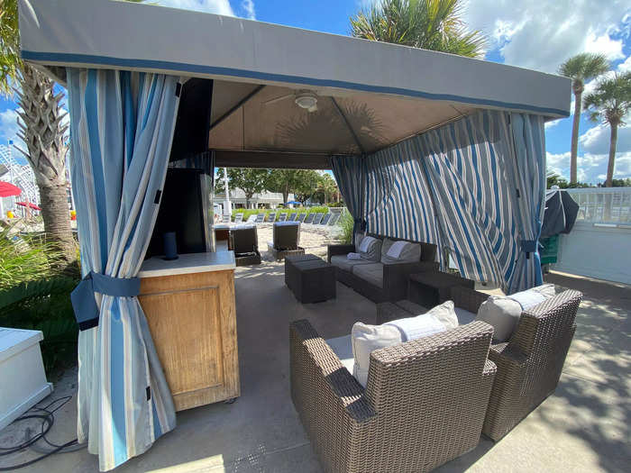 The cabana is equipped with a shaded sitting area and two lounge chairs in the sun.