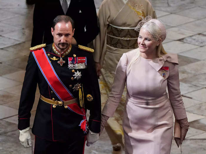 Crown Princess Mette-Marit of Norway wore a light pink midi dress with a decorative bow while Crown Prince Haakon wore military regalia.