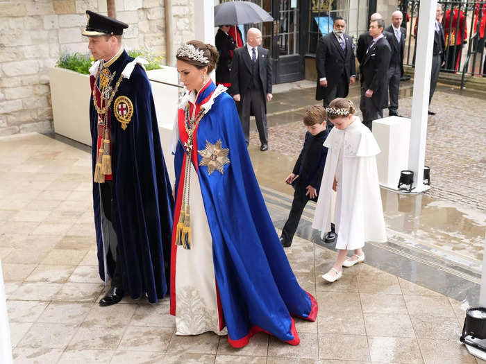 Kate Middleton wore a formal blue cape over an ivory dress designed by Alexander McQueen, while Prince William wore a military uniform with ceremonial robes.