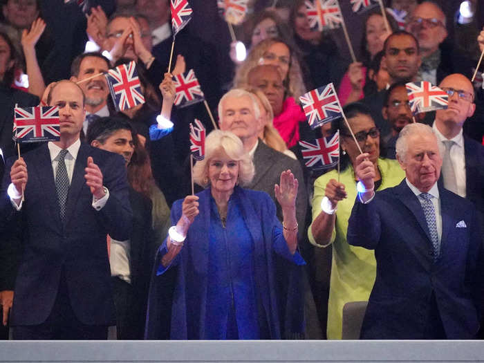 King Charles and Prince William waved their Union Jack flags while Queen Camilla appeared to wave her hand in time to the music.