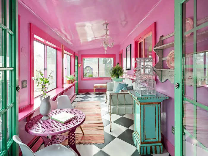 The sun room towards the back of the house has black-and white-tiles that contrast the pink walls and window casings.