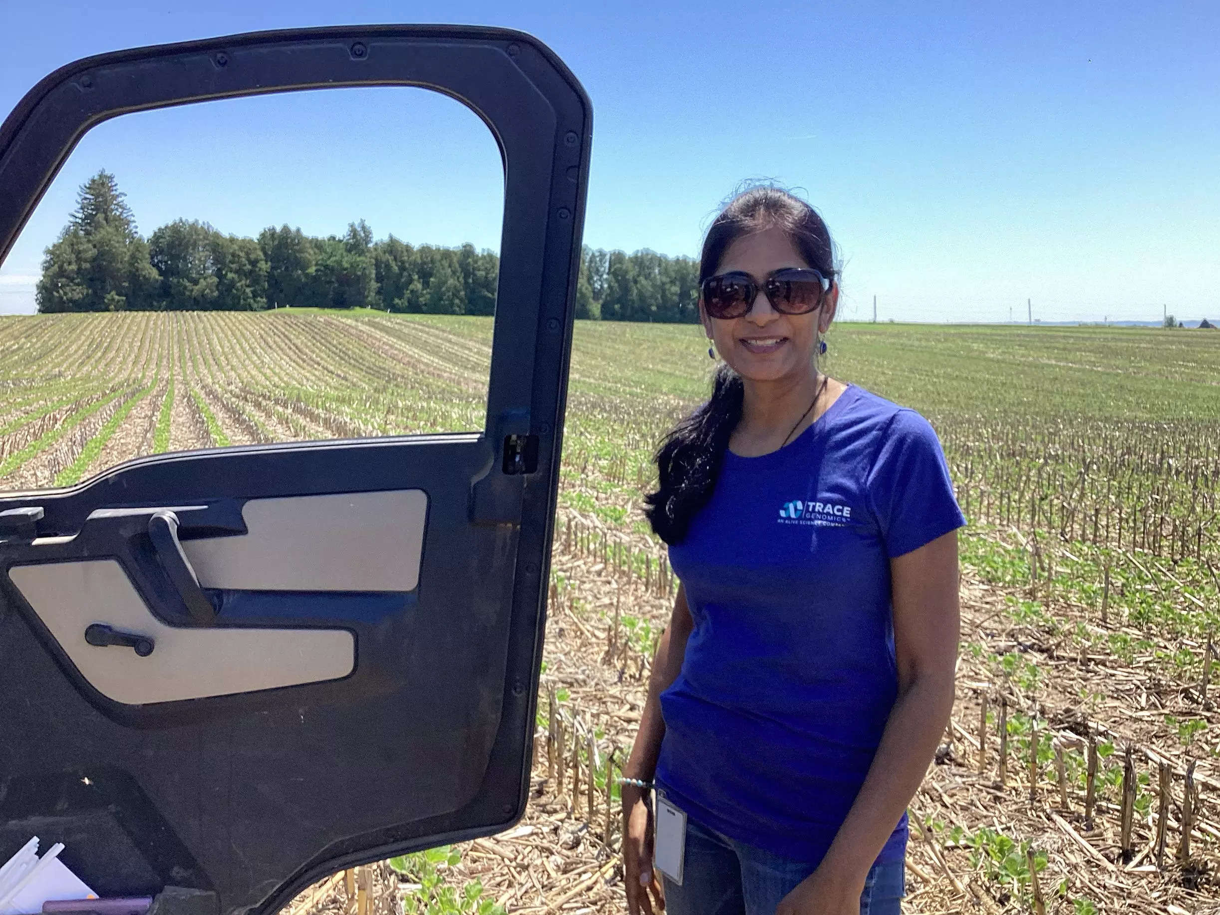 A woman wearing a Trace Genomics t-shirt stands in a field.
