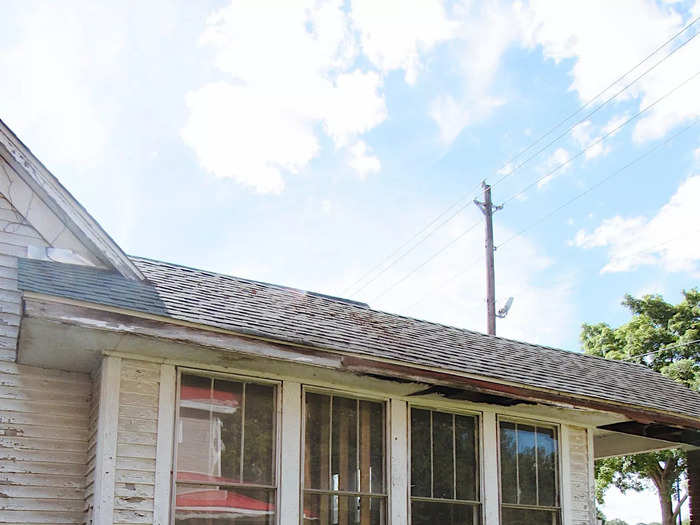 A side of the house with worn-out siding and dirty windows