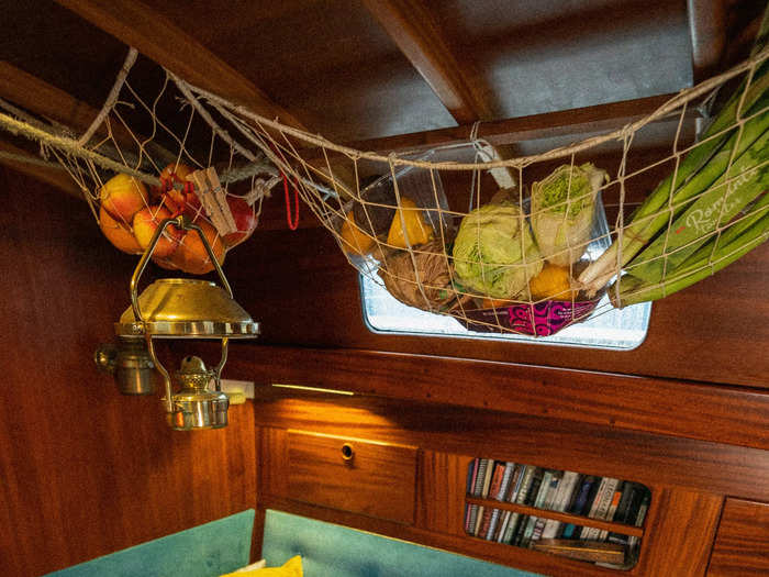 For a unique way to make space, they hang produce above their living and dining area. There is some hidden storage in the woodwork as well.