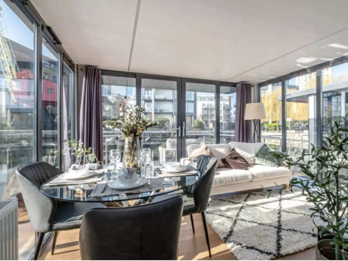 The living room has ceiling to floor windows, offering sweeping views of the waterfront