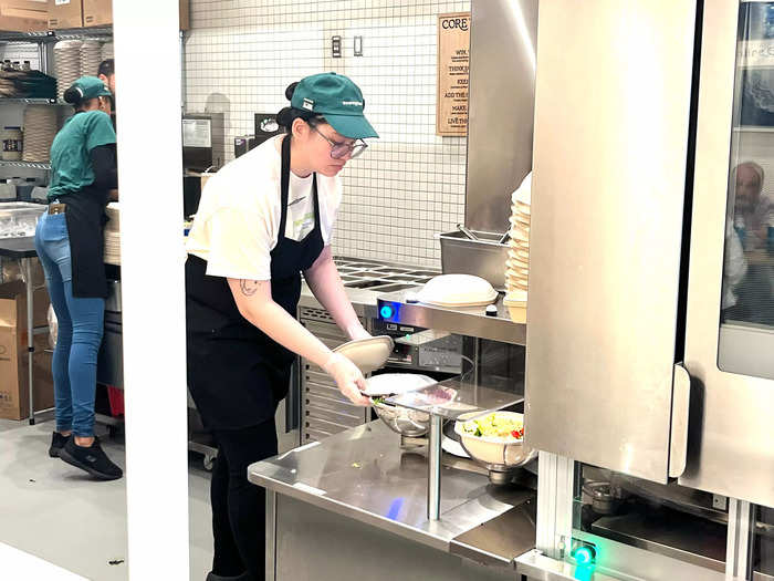 Look, a human! At this point in the process, an employee stepped in to put the final touches on the orders. They added sides of dressing and additional garnishes.