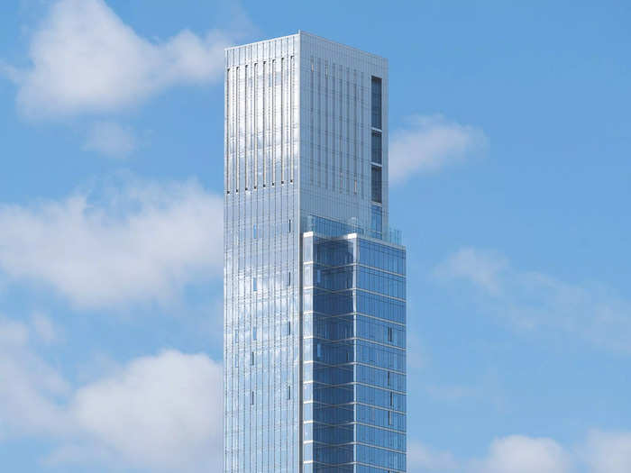 The glassy top floors of Central Park Tower blend into a blue sky with clouds