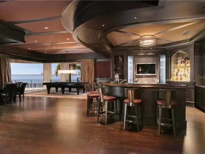 The sleek clubroom features a full-service bar, pool and game tables, TVs, and views of the bay.