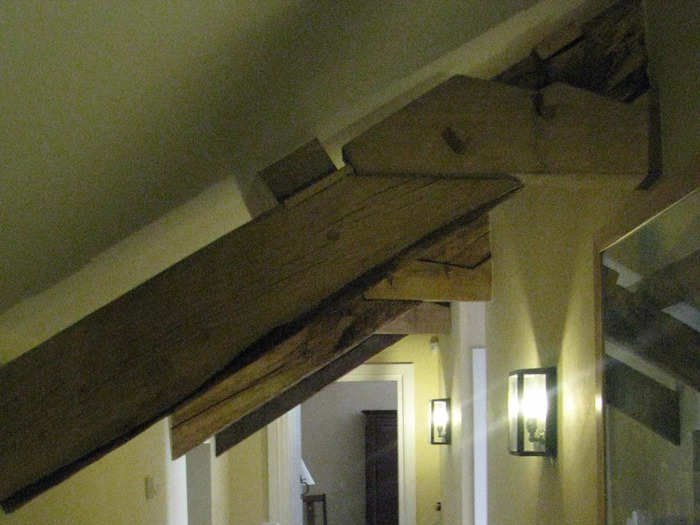 Another image shows exposed wooden beams along the upstairs landing, which is painted yellow.