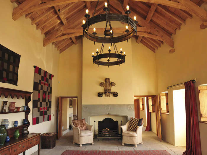 The main reception room has high ceilings and a large log fireplace. Queen Camilla