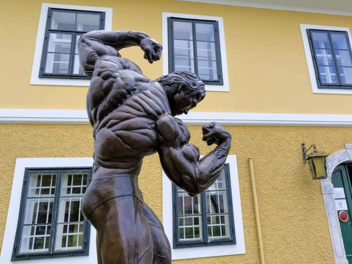 Outside the home is a large bronze statue depicting Schwarzenegger in the 3/4 back pose — a pose he made famous.