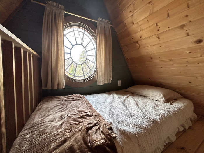 The other bed on this floor is positioned directly below a beautiful circular window.