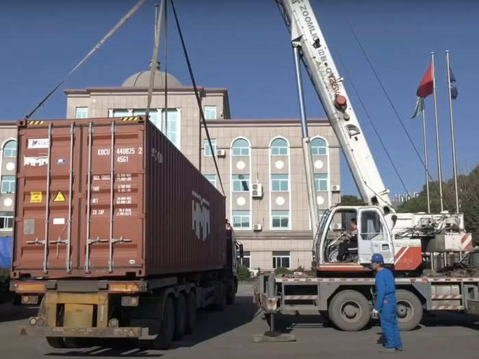 After leaving the factory, the foldable home is trucked to its final location where a crane operator lifts it and places it on the ground.