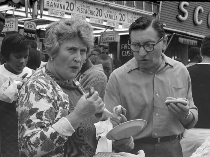 In this circa-1968 photograph, a couple eats hot dogs in front of Nathan