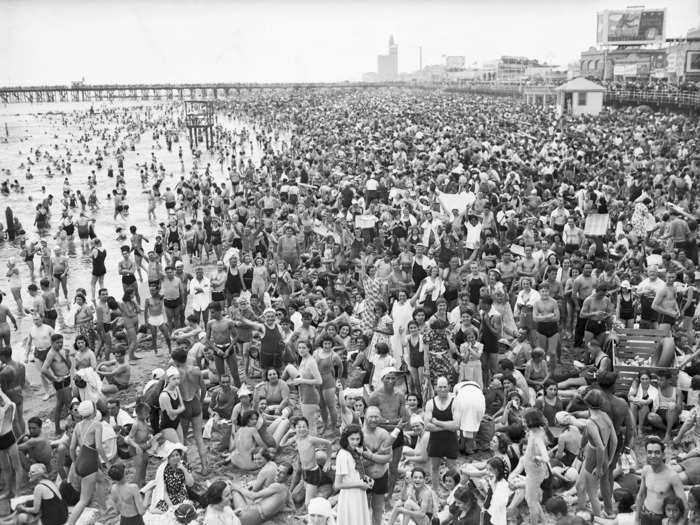 A photo taken on July 4, 1938, shows crowds of people gathered together on the beach. There are so many people, you can hardly see the sand.