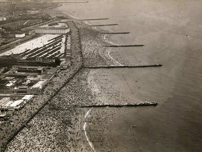 In a black-and-white aerial photo from 1920, you can see thousands of people gathered on the boardwalk and Coney Island Beach during the Fourth of July.