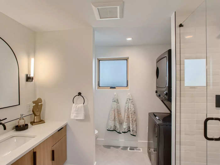 The bathroom has a walk-in shower, a white countertop, and black accents. There