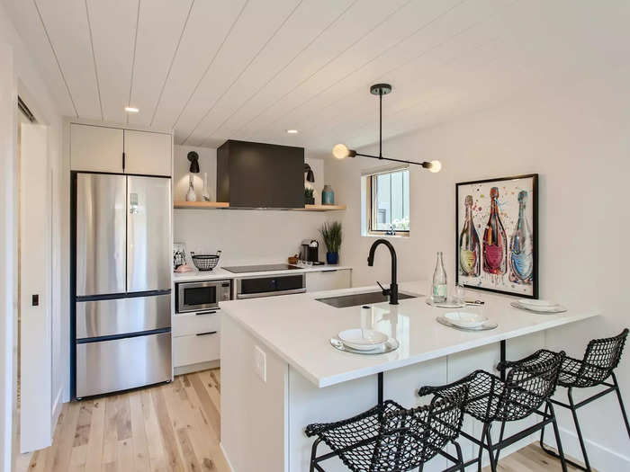 The kitchen has stainless steel appliances as well as a sleek black stove hood, faucet, and light fixtures.