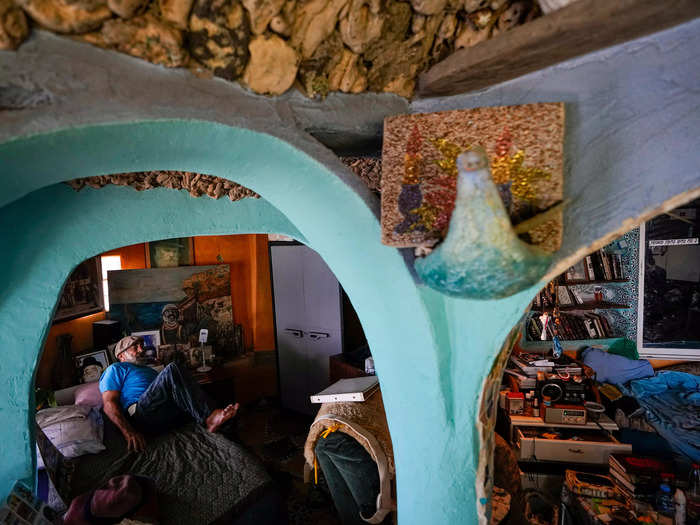 The interiors of the cave home are decorated with colorful glass shards, mosaic tiles, and broken pieces of pottery.