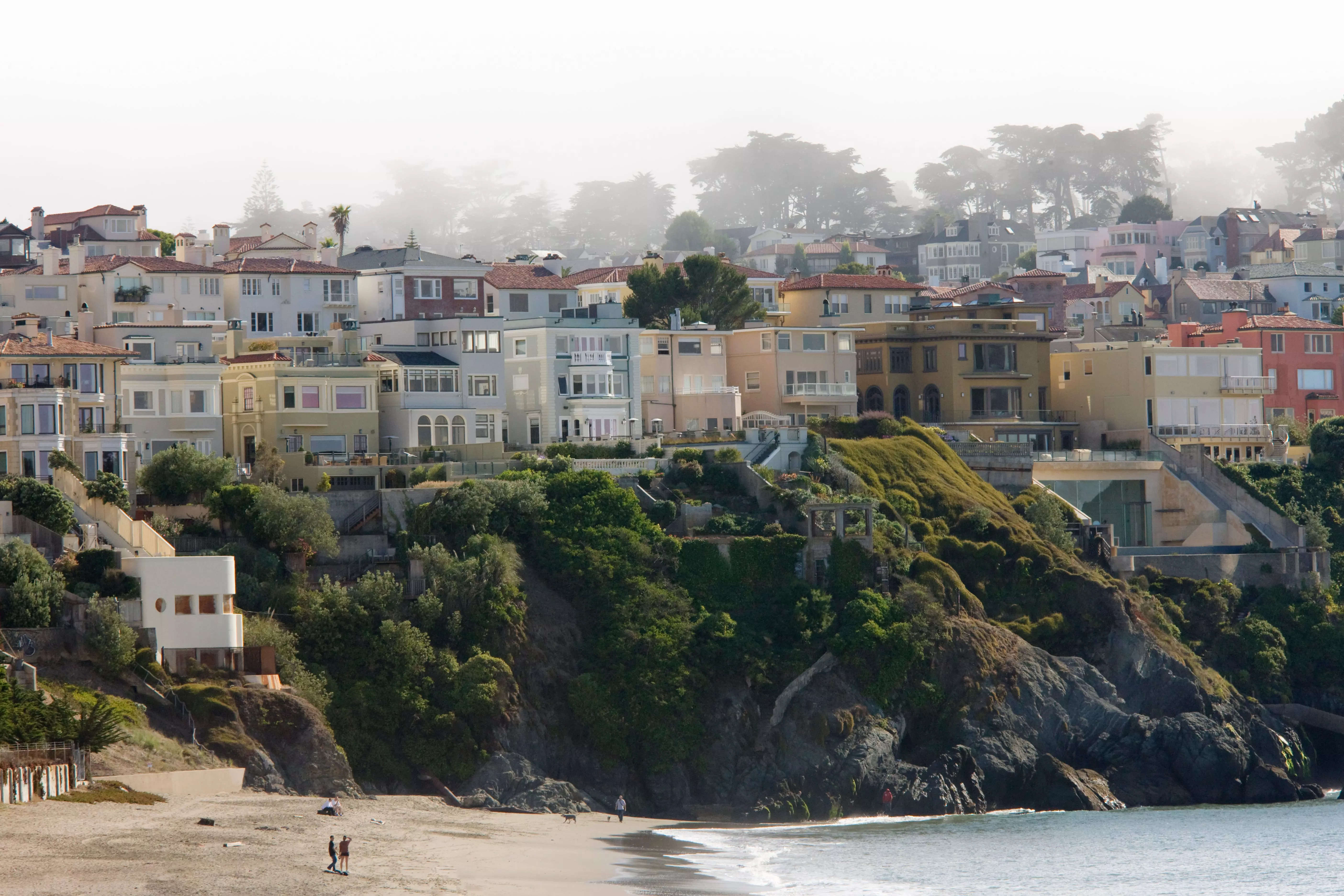 Rows of pastel homes on a beach overlooking a cliff