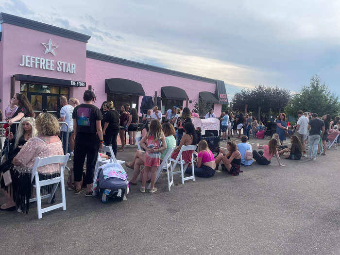 Some people around me grabbed chairs from tables that had been set up in front of the nearby food stand to sit on while they waited in line.