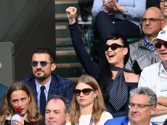 Katy Perry and Orlando Bloom attended the event in coordinating navy-blue ensembles and sunglasses. Bloom wore a checkered jacket with a shirt and tie, while Perry wore a retro, polka-dot scarf.