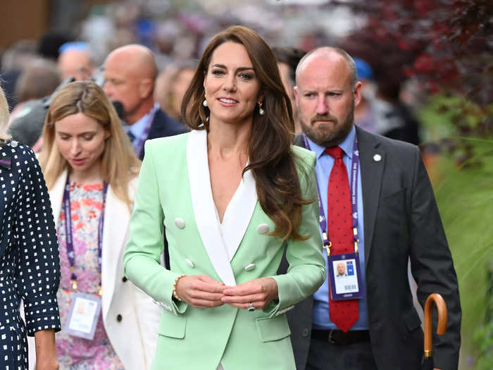 Kate Middleton opted for a splash of color in a mint-green, Balmain blazer with white lapels and oversized buttons. She paired the jacket with a white pleated skirt, pointed-toe pumps, and pearl drop earrings.