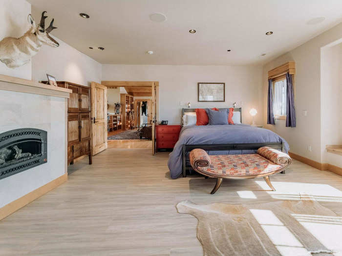 One of the bedrooms is on this floor. It features a mounted deer head, fireplace, and wood accents.