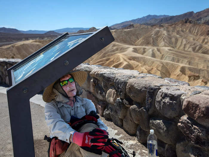 Here, one recent tourist, a 71-year-old hiker, tried to take a break from the soaring temps underneath a visitor signpost. His face was covered in sunscreen and he wore a sunhat, long sleeves, and gloves to protect himself from the sweltering heat.