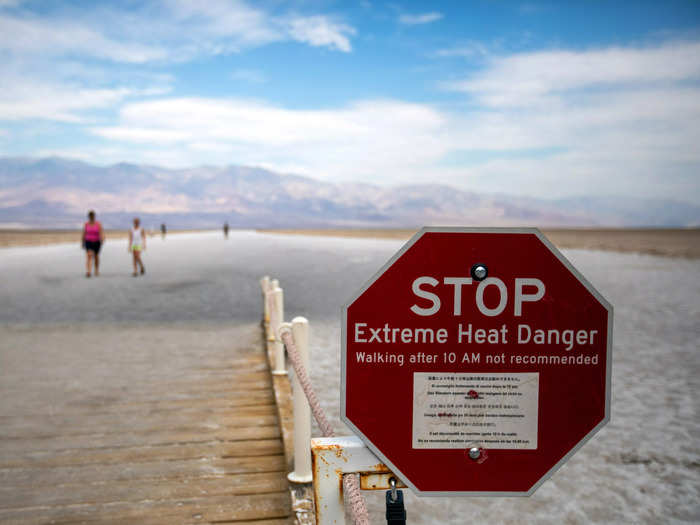 Some photos from over the weekend give context to the danger of visiting Death Valley. This image shows tourists roaming the arid plains behind an "Extreme Heat Danger" sign warning people not to walk through the area after 10 a.m.