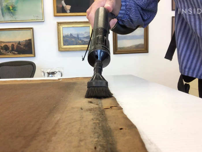 The canvas is vacuumed to remove decades of dust, grime, and debris.