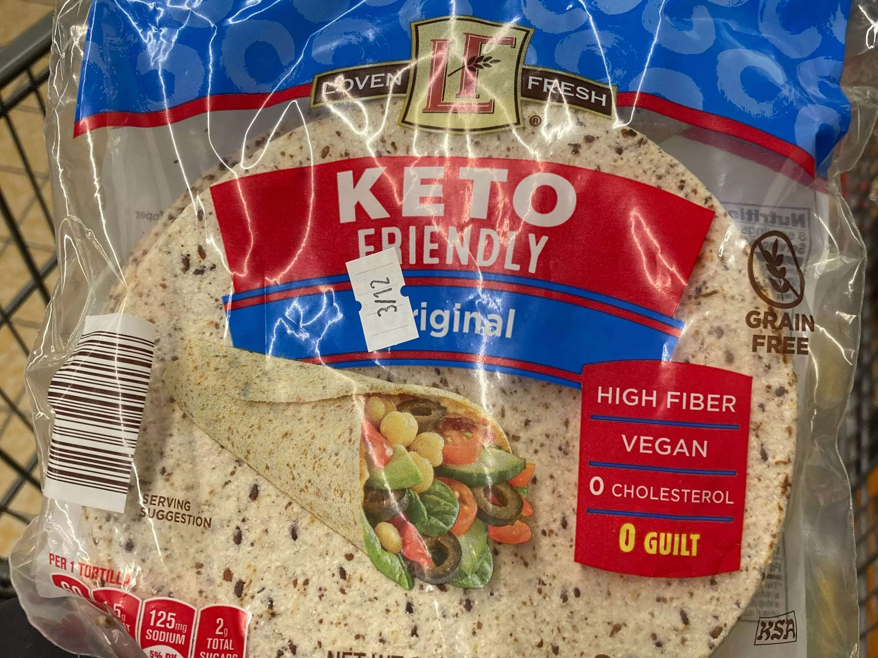 hand holding red, blue, and clear package of loven fresh keto wraps at aldi