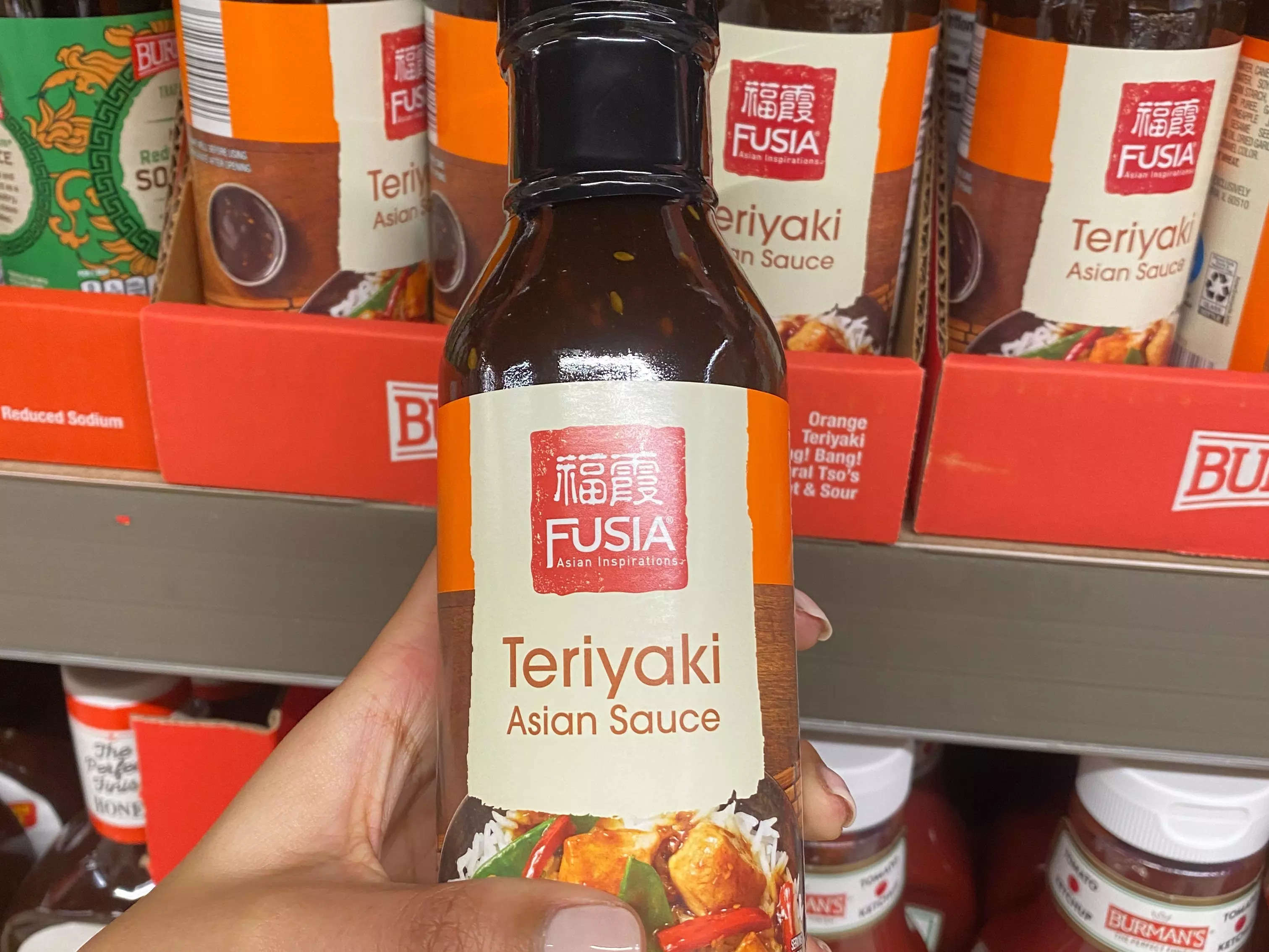 Hand holding bottle of Teriyaki sauce at Aldi