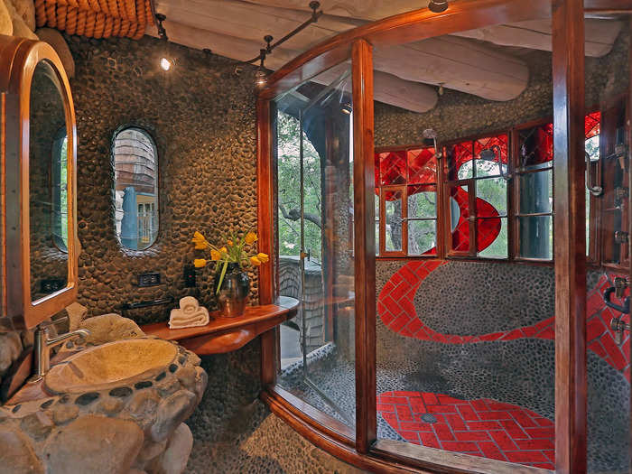 A bright red wave of tiles cuts through the primary suite bathroom, with a private balcony off to the side.