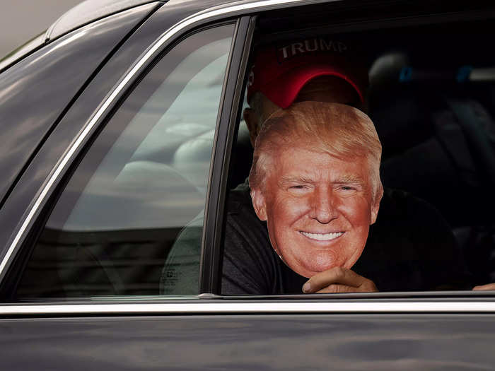 A Trump supporter held up a mask of the former president. He was also riding in a black car that was adorned with a facsimile Seal of the President on the passenger door.