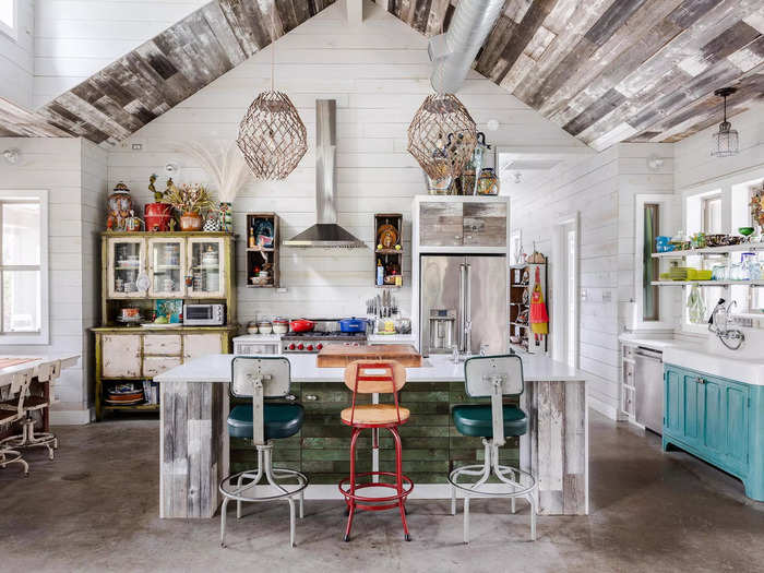 The reclaimed wood ceilings extend into the kitchen area, where ample windows let light stream in.