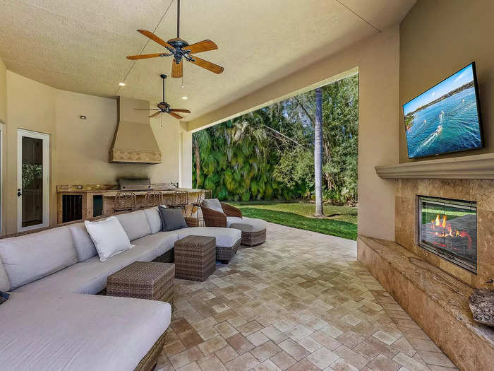 Adjacent to the pool, there is an outdoor TV area with a fireplace and kitchen.