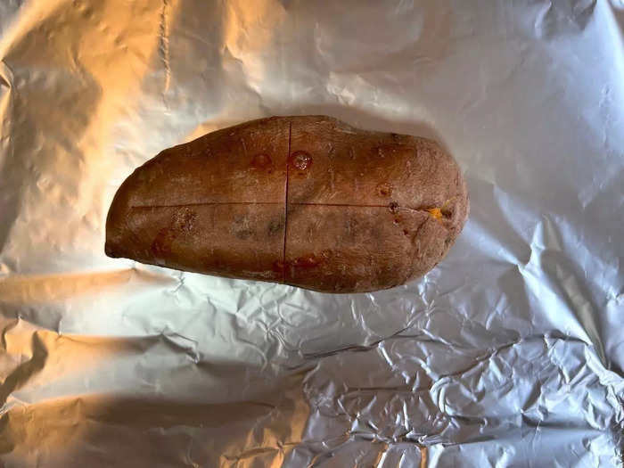 Next, slice the potato lengthwise and crosswise down the center with a sharp knife — without cutting all the way through. Wrap the potato tightly in foil, and pop it in the oven for 20 minutes.