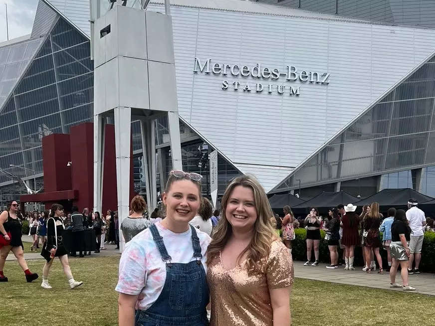 The writer poses with a friend in front of the Mercedes-Benz stadium in Atlanta