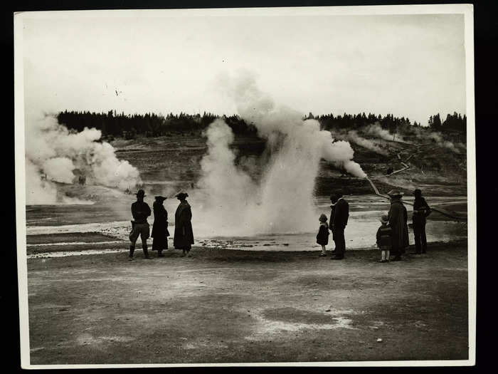 Tourists stand very close to a geyser basin at Yellowstone National Park in 1920.