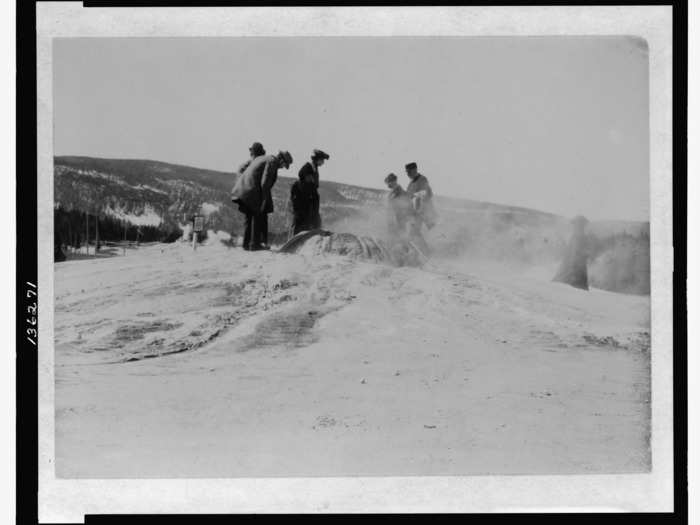 A group of tourists inspect a geyser at Yellowstone National Park