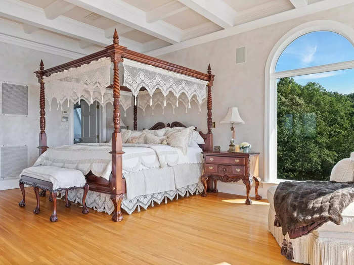 In the bedrooms, like this master suite, there are arched doorways, white walls, and beamed ceilings.