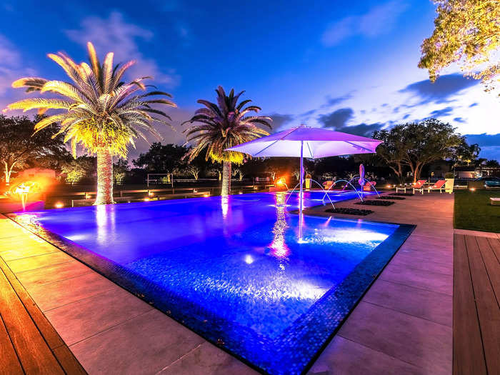 The pool, which is flanked by palm trees, and the rest of the yard can be illuminated for optimal night-time enjoyment.