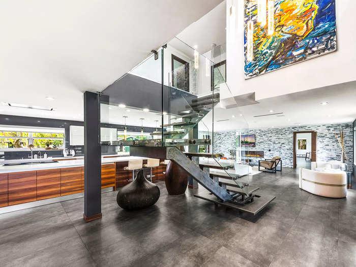 The kitchen, seen behind the staircase, features Italian Calacatta quartz countertops, an integrated refrigerator and oven, and a built-in bar.