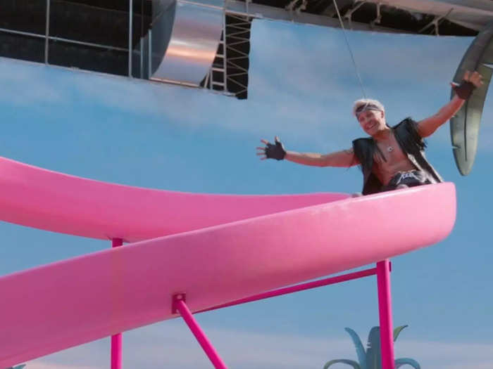 Gosling appears to be in a harness while going down the slide.