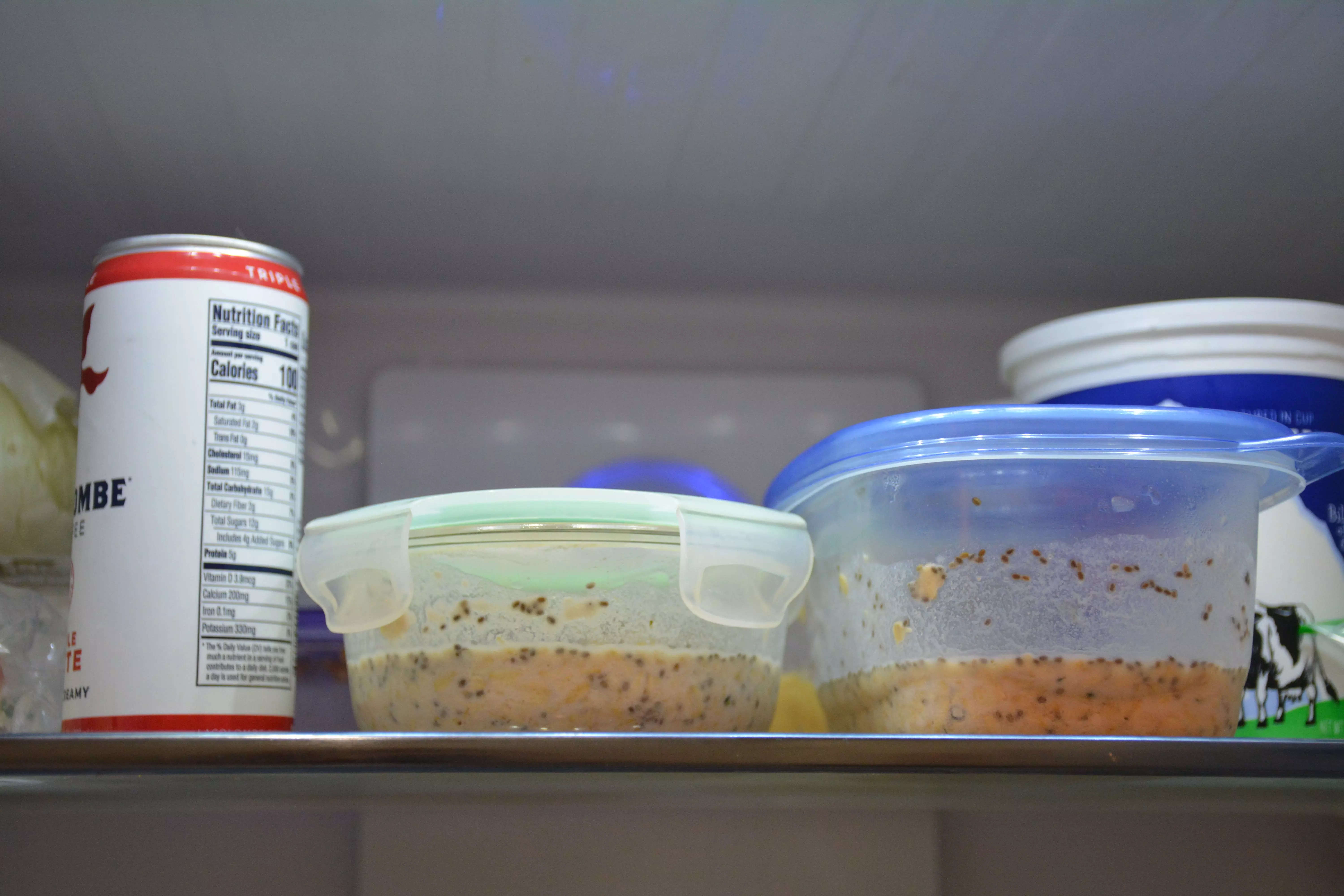 Two Tupperware of overnight oats on the upper shelf of the fridge.